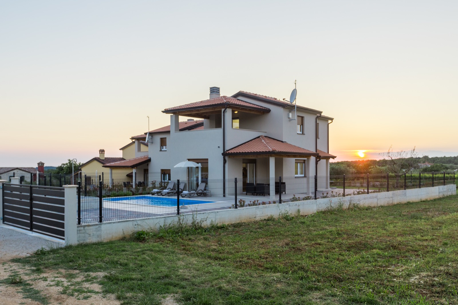 Villa Alcove at sunset, seen across the lawn with the pool in front